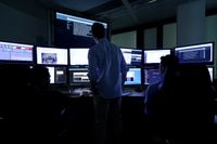 Multiple people monitoring screens in the control room