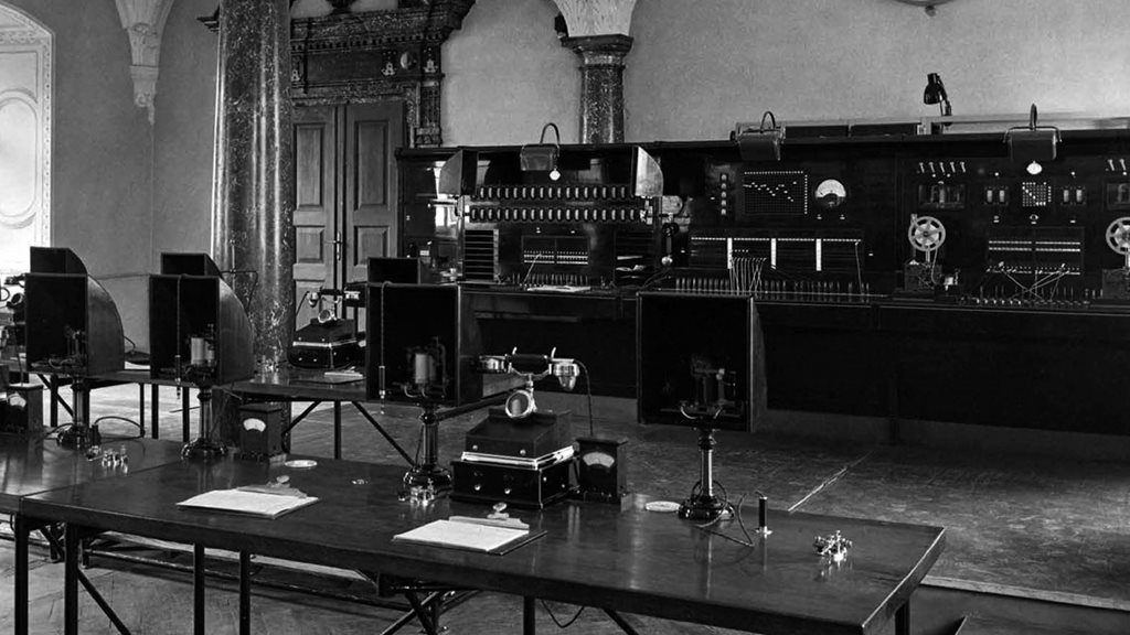 Una sala de reuniones con una mesa grande y sillas, capturada en blanco y negro.