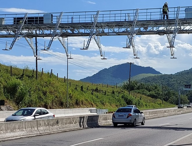Auto fährt auf einer Straße, während ein Mann auf einer Brücke steht.
