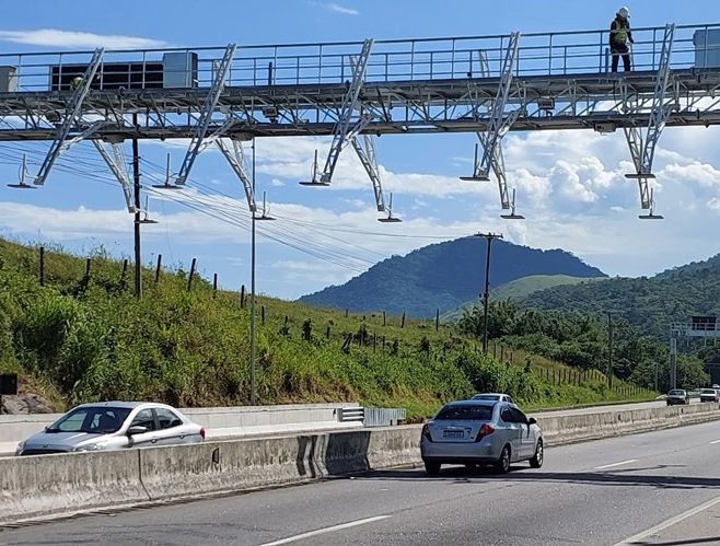 Auto fährt auf einer Straße, während ein Mann auf einer Brücke steht.