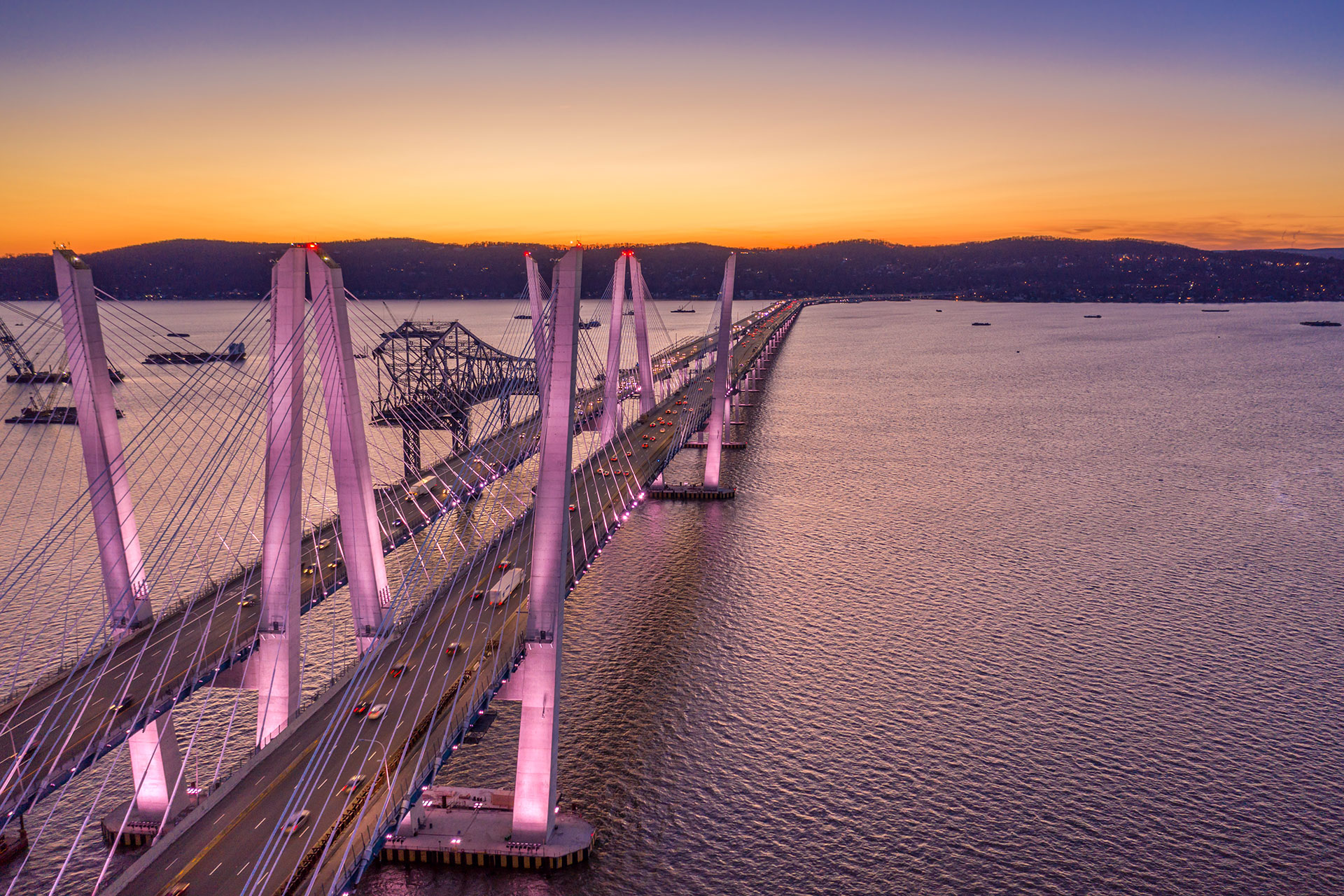 © Kapsch TrafficCom Beleuchtete Brücke über Wasser bei Sonnenaufgang.