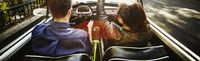 Couple driving convertible on city boulevard KTC3254-1920x582