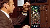 Un hombre reparando una computadora en un contexto histórico de innovación tecnológica de Kapsch.