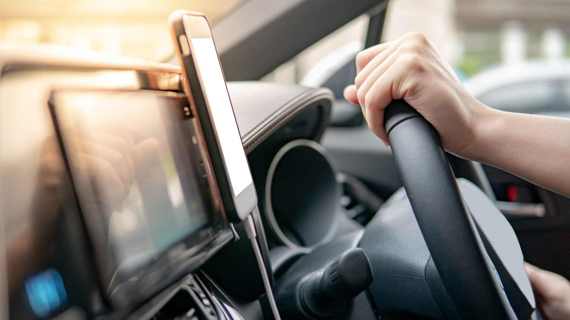 A person driving a car, holding the steering wheel, illustrating Kapsch TrafficCom's road user charging solution.