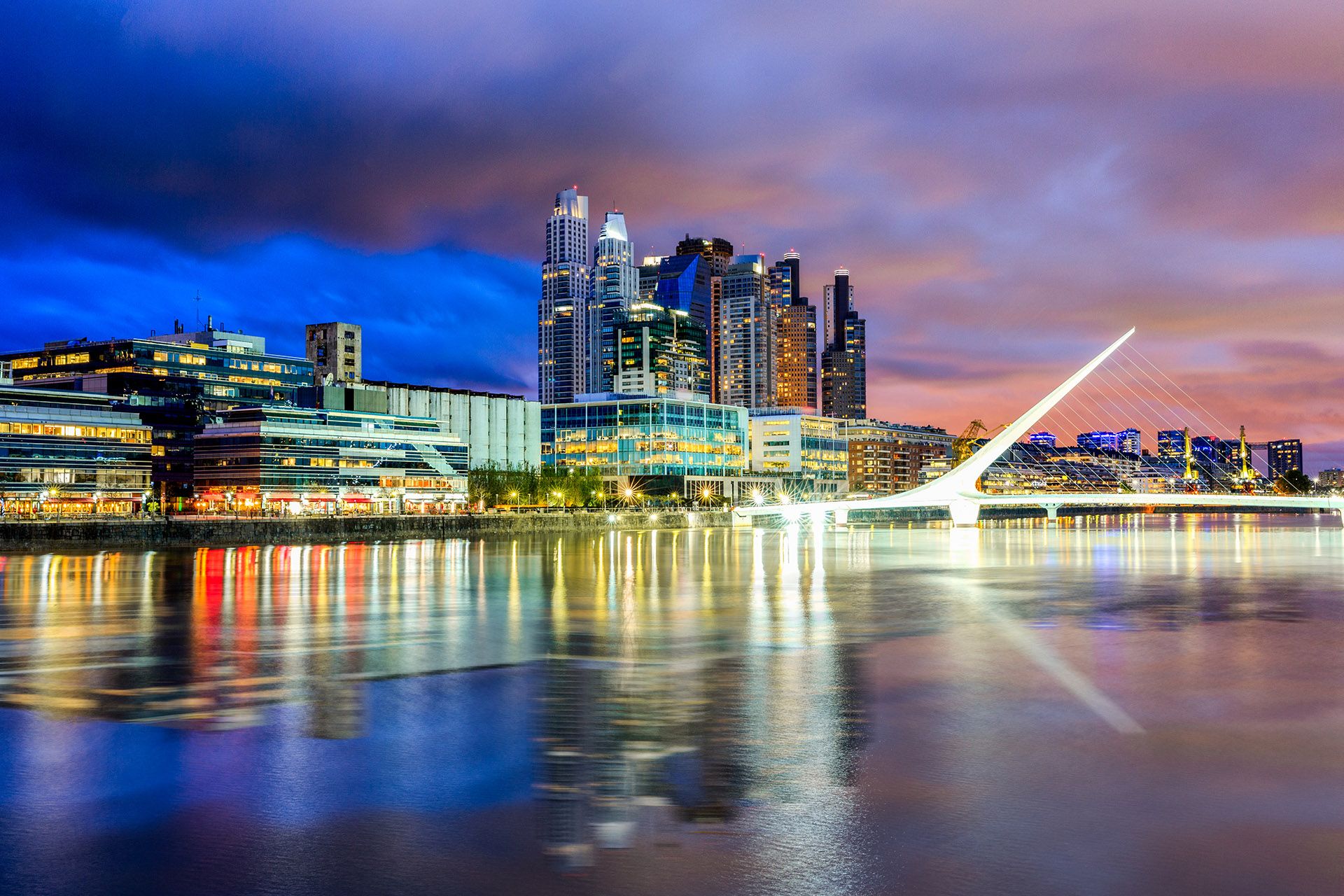 Eine Brücke über Wasser mit einer Stadt im Hintergrund.