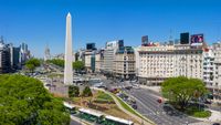 Straße mit dem Obelisco de Buenos Aires, umgeben von Bussen und Autos.