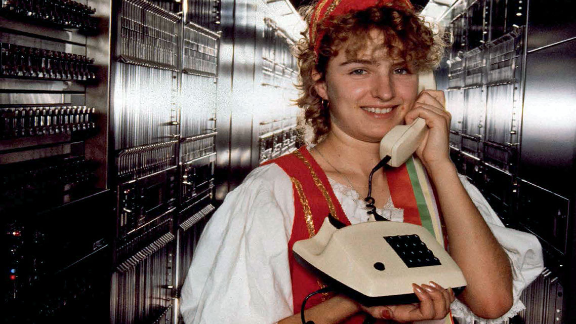 Una mujer sonriendo mientras sostiene un teléfono en un ambiente interior.