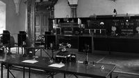 Una sala de reuniones con una mesa grande y sillas, capturada en blanco y negro.