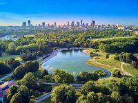 Ein Park mit einem Teich und einer Stadt im Hintergrund.