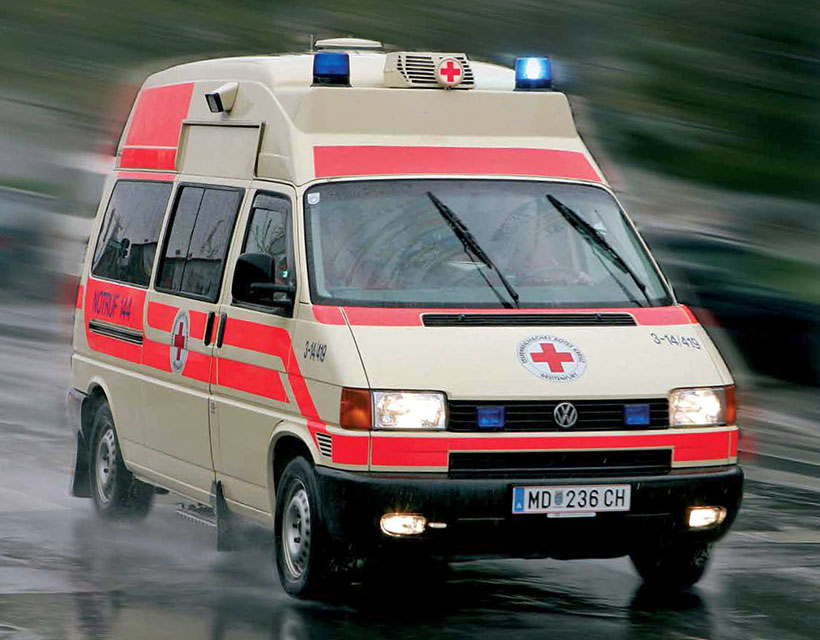Una ambulancia blanca y roja en una carretera mojada.