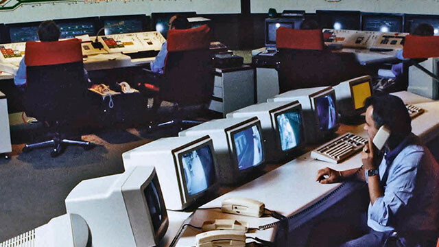 Un grupo de personas trabajando en computadoras en una sala, reflejando la innovación tecnológica de Kapsch a lo largo de su historia.