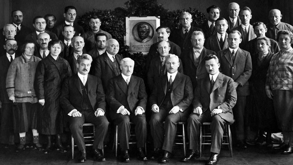Un grupo de hombres en trajes, posiblemente miembros de la dirección de Kapsch, posando juntos en un entorno formal.