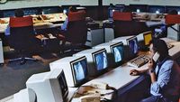 Un grupo de personas trabajando en computadoras en una sala, reflejando la innovación tecnológica de Kapsch a lo largo de su historia.
