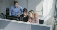 Eine Gruppe von Menschen betrachtet einen Computerbildschirm.