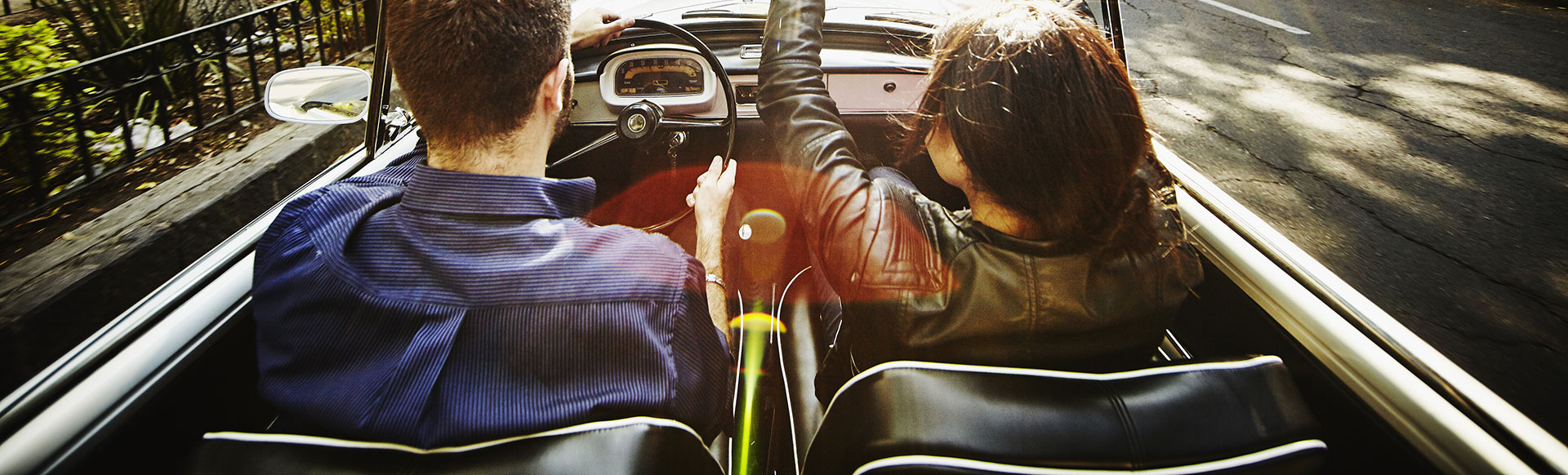 Couple driving convertible on city boulevard KTC3254-1920x582