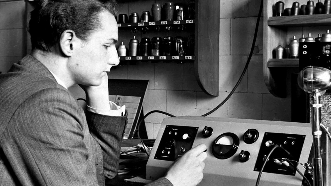 Un hombre trabajando en una máquina en un entorno industrial, representando la innovación tecnológica de Kapsch a lo largo de su historia.
