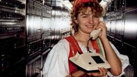 Una mujer sonriendo mientras sostiene un teléfono en un ambiente interior.
