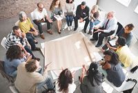 Un grupo de personas sentadas en círculo discutiendo estrategias de ventas en Kapsch TrafficCom.