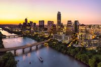 Stadt mit Brücke über Wasser im Vordergrund und Skyline im Hintergrund.