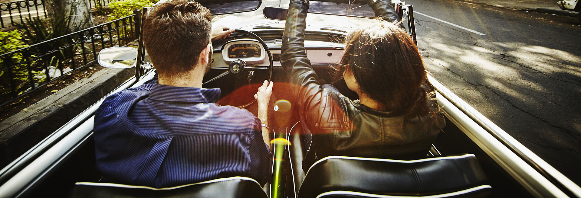 Couple driving convertible on city boulevard KTC3254-1920x656
