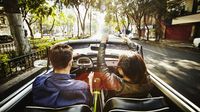 Couple driving convertible on city boulevard KTC3254-1920x1079