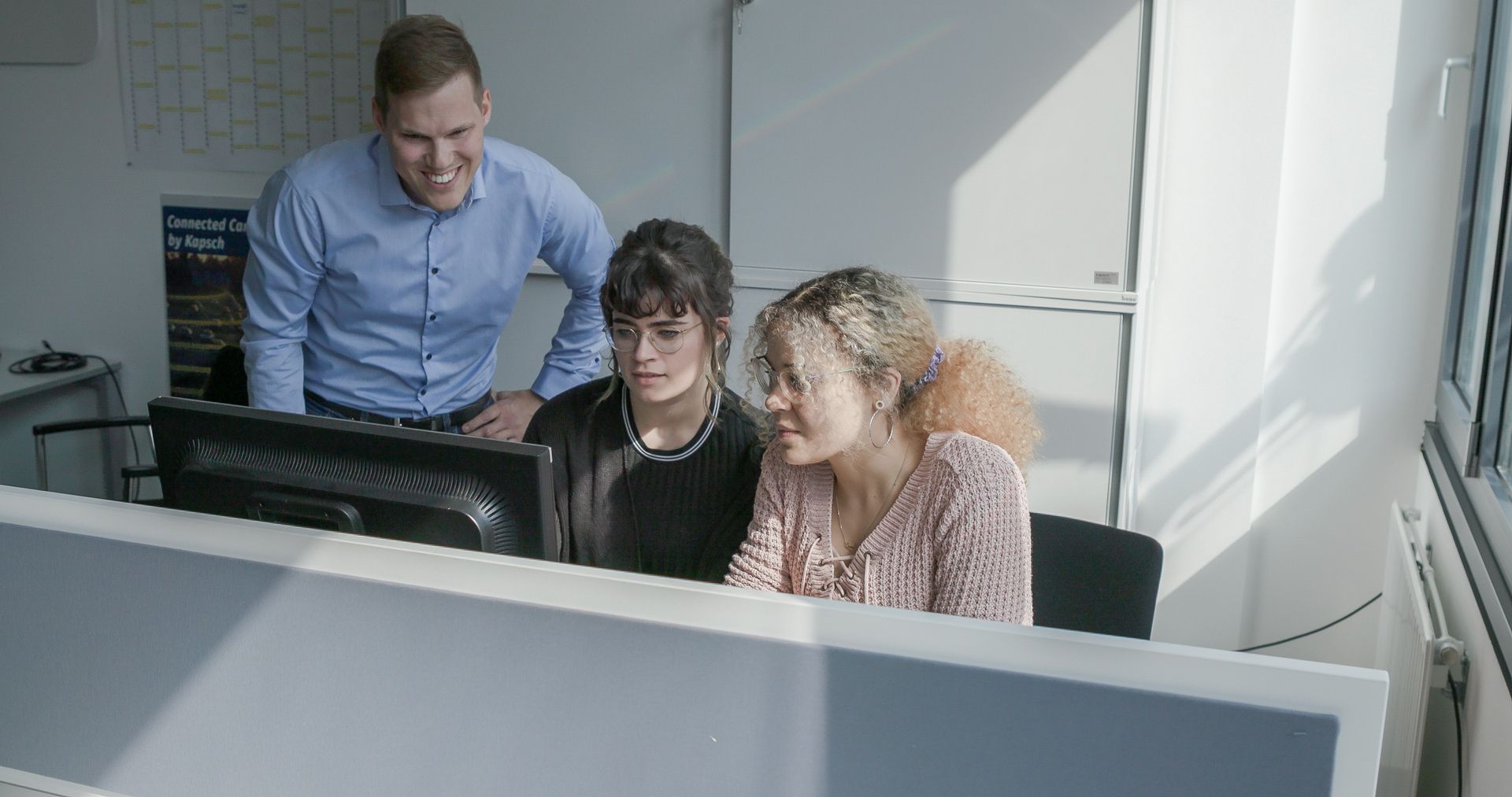 Eine Gruppe von Menschen betrachtet einen Computerbildschirm.