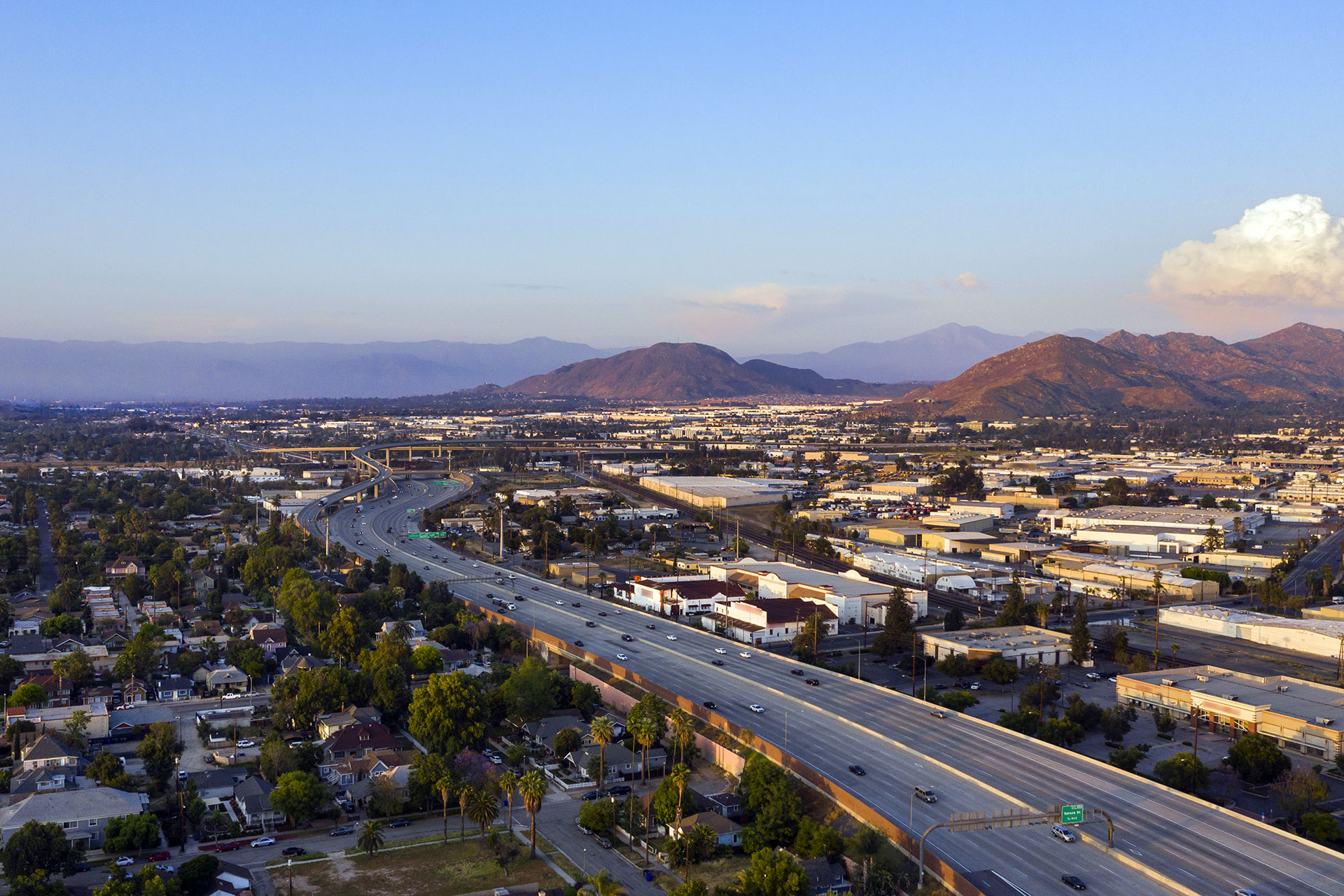 Luftaufnahme einer Autobahn in einer Stadt mit umgebenden Gebäuden und Bergen im Hintergrund.