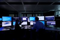 Two people monitoring screens in the control room