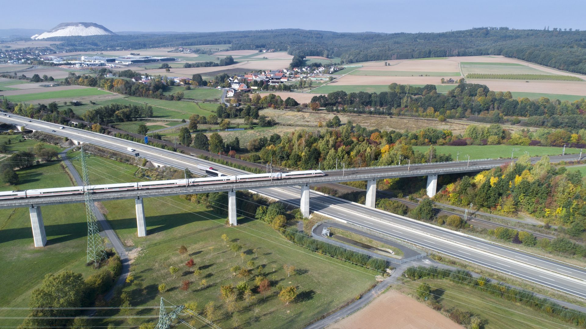 Ein Zug auf einer Brücke über einer Autobahn.