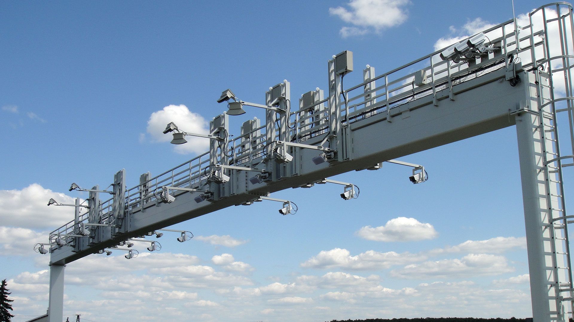 Gantry over a highway with cloudy sky in the background.