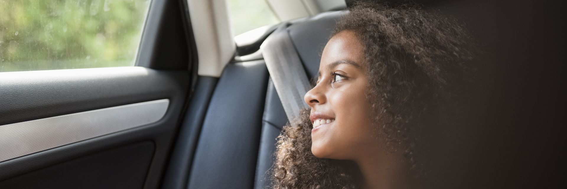 A woman smiling inside a car, illustrating Kapsch TrafficCom's vision for innovative transportation solutions.