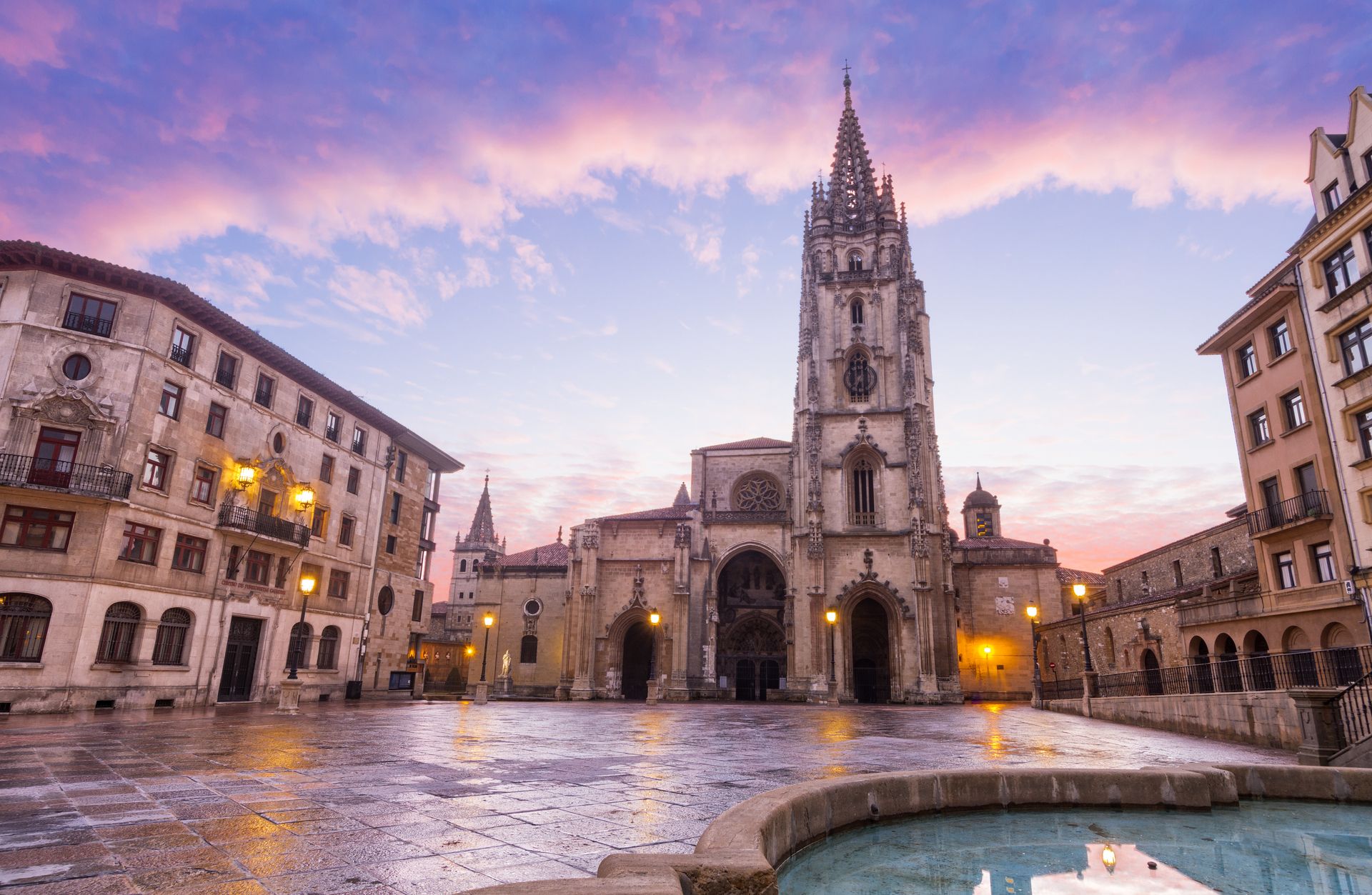 Ein großes Gebäude mit einem Turm und einem Brunnen davor.