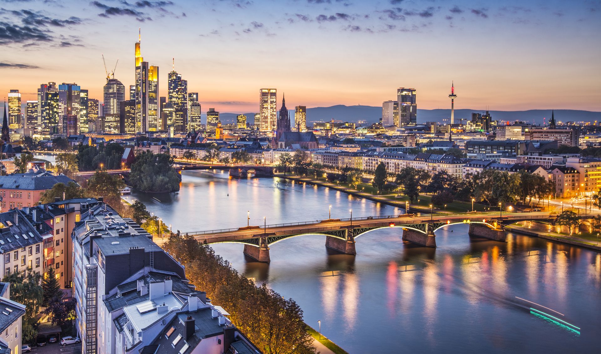 Stadtansicht mit einer Brücke über einen Fluss bei Sonnenuntergang.