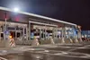 A gas station at night, highlighting the building and illuminated gas pumps.