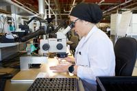 A woman technician looking through a microscope in a research institute.