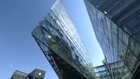 Glass-walled commercial building against a clear sky.