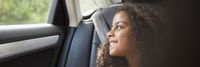 Una mujer sonriendo dentro de un coche en el contexto de la visión y misión de Kapsch sobre movilidad sostenible.
