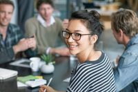 A woman smiling confidently, representing the diverse and inclusive work environment at Kapsch TrafficCom Austria.