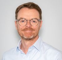 Ein Mann mit Brille lächelt.