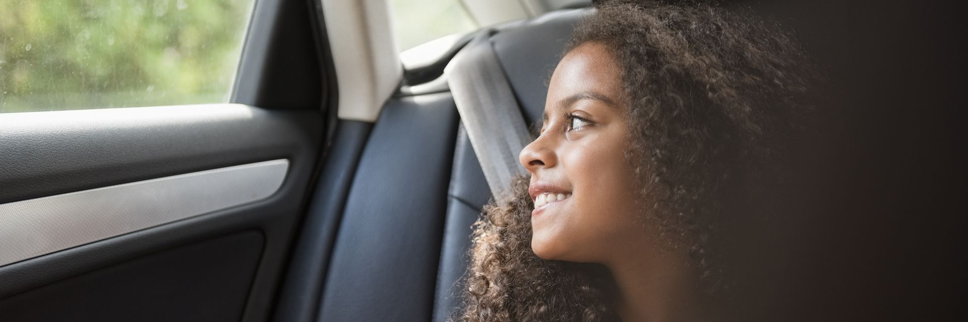 Eine Frau in einem Auto, die aus dem Fenster schaut, symbolisiert die Vision und Mission von Kapsch TrafficCom für innovative Mobilitätslösungen.